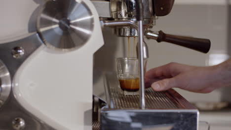 un hombre está haciendo un vaso de espresso en una máquina de espresso durante el día