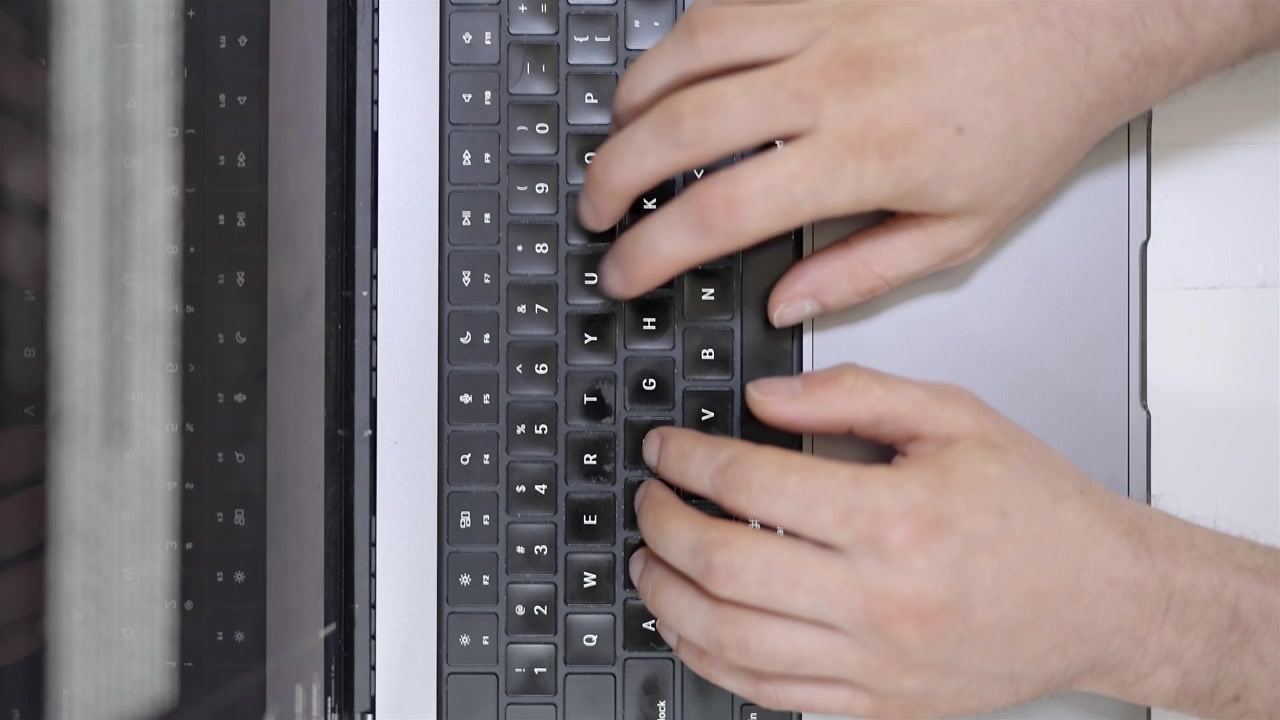 Overhead view of hand holding coffee mug next to laptop on white desk