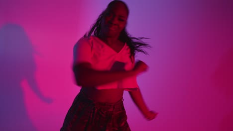 studio shot of young woman dancer dancing against blue and pink lit background 5