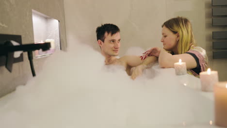 couple relaxing in a bathtub with bubbles and candles