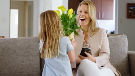 hija dando una flor a su madre en la sala de estar