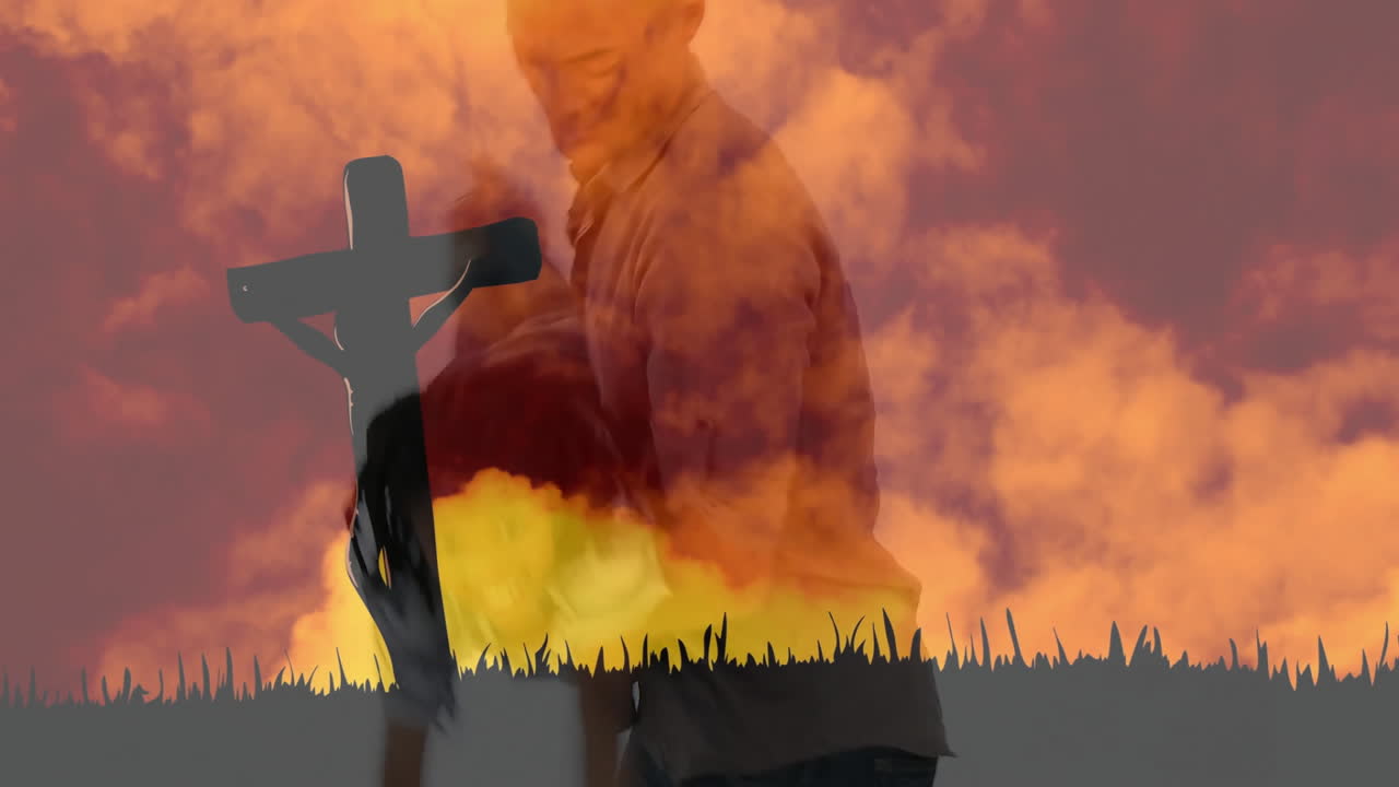 Standing against dramatic orange sky, silhouette of person with cross