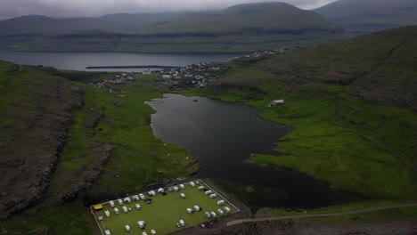 Abandoned-football-pitch-Eidi-campsite-on-Faroe-Islands-coast,-aerial-reveal-view