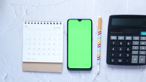 Offener-Kalender-Und-Smartphone-Mit-Grünem-Bildschirm-Auf-Dem-Tisch,