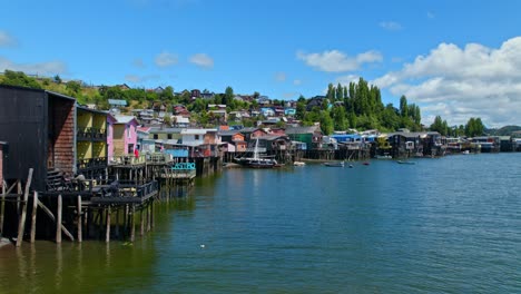 drone flying toward a ship in front of the palafitos stilt houses of castro, chile