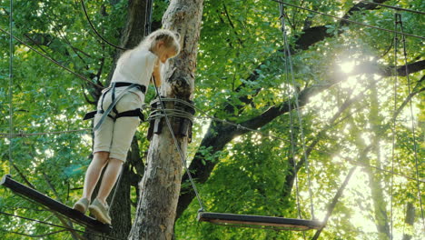 a brave child walks along a tightrope between tall trees active childhood and fun