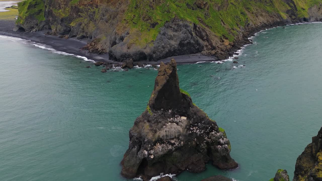 4K Cinematic drone shot over Reynisfjara Beach, capturing the contrast between the dark volcanic shore, turquoise waves, and dramatic cliffs under moody Nordic skies - Iceland_39
