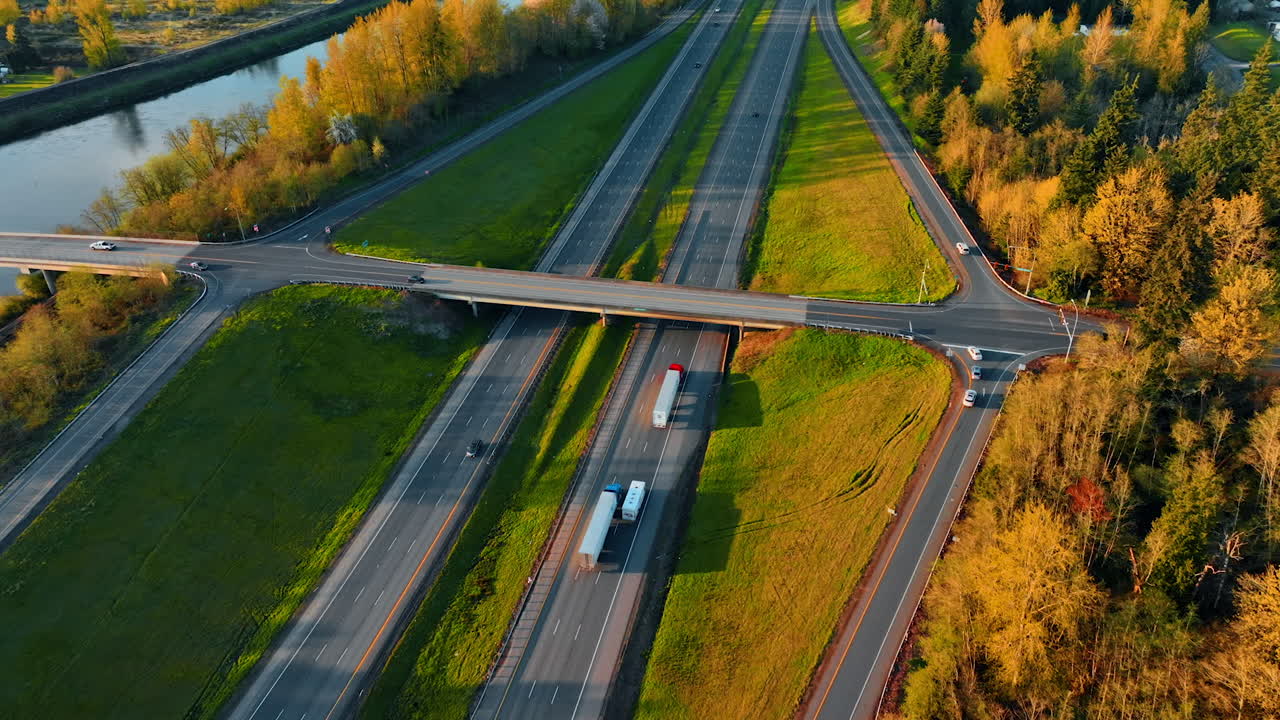 Transport moves by the highways outside the big cities. Aerial perspective on the roads built along the narrow river in Oregon State, USA.