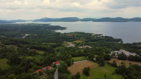 aerial flyover plastira lake in greece with green landscape and mountains during cloudy day - panning shot