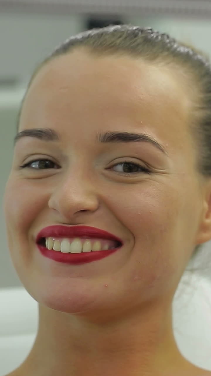Woman Looking In The Mirror. A woman looks in the mirror and enjoying her smile