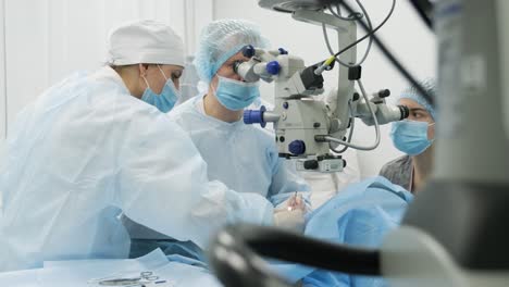 equipo de cirugía haciendo cirugía de estrabismo utilizando tecnologías modernas, dispositivos más recientes, microscopio en una clínica moderna
