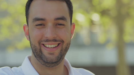 Smiling-bearded-man-talking-to-camera-outdoor.