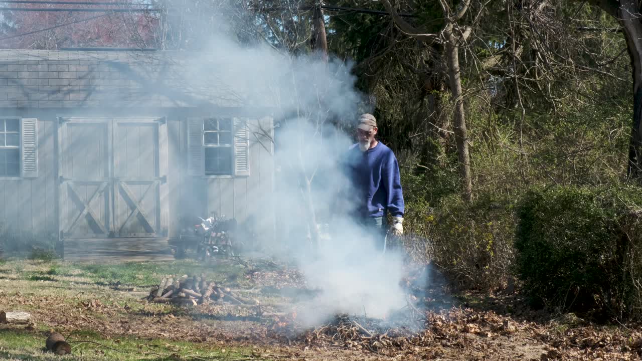 한 남자가 모닥불이 타오르는 것을 면밀히 지켜보며 불에 연료를 더하기를 기다리고 있습니다.