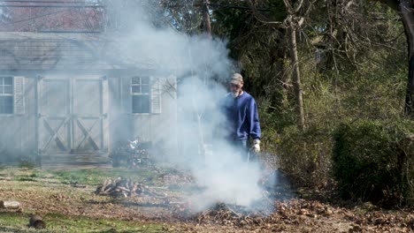 un hombre observa de cerca cómo arde su hoguera, esperando agregar más combustible al fuego