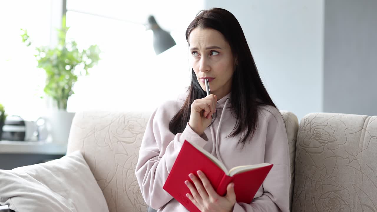 Woman reading a red book on a sofa
