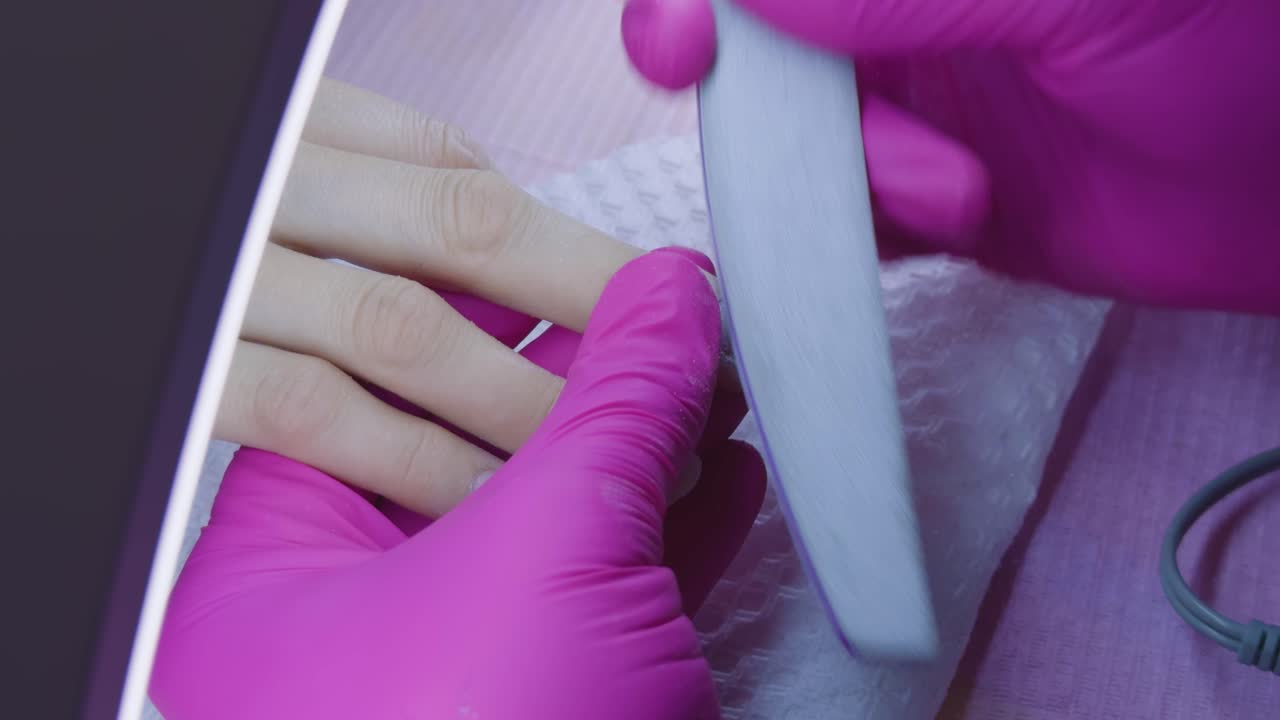 Manicurist filing her client's nails at home. Home care. Close-up shot