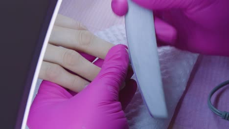 manicurist filing her client's nails at home. home care. close-up shot