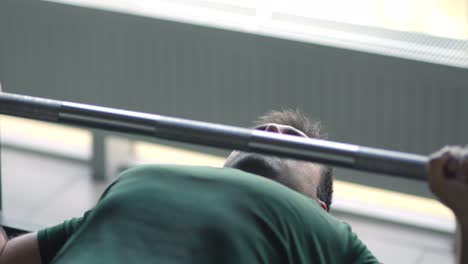 man performing bench press exercise in gym