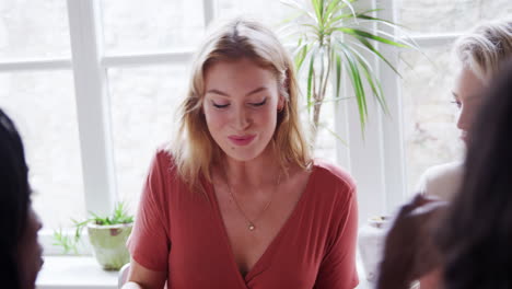 Young-adult-woman-drinking-wine-and-having-lunch-with-her-friends-in-a-restaurant,-close-up