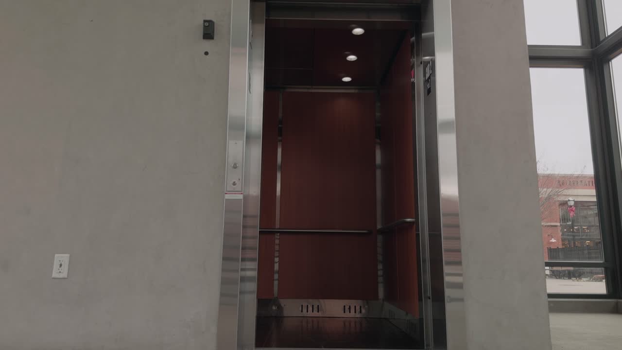 Plano estático a cámara lenta de las puertas de un ascensor que se abren, se detienen y se cierran dentro de un edificio moderno