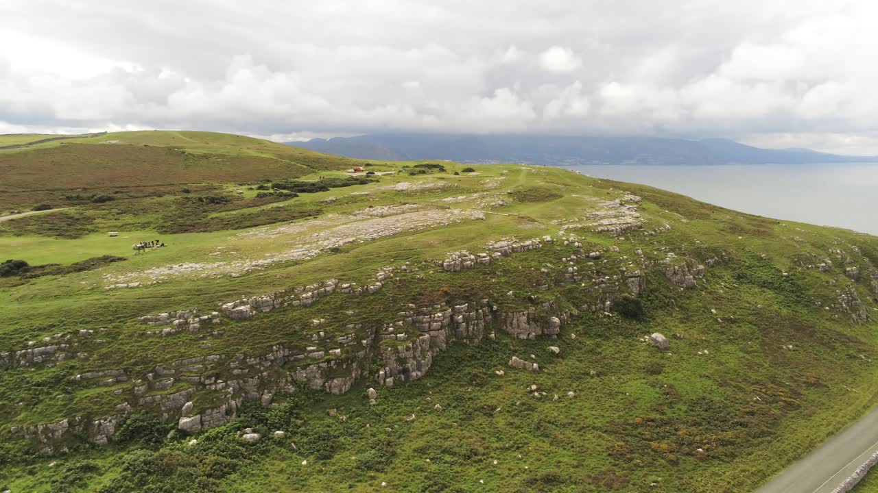 Luftfoto: Droneflyvning over Great Orme Llandudno bjergdal, stiger op over landligt landskab.
