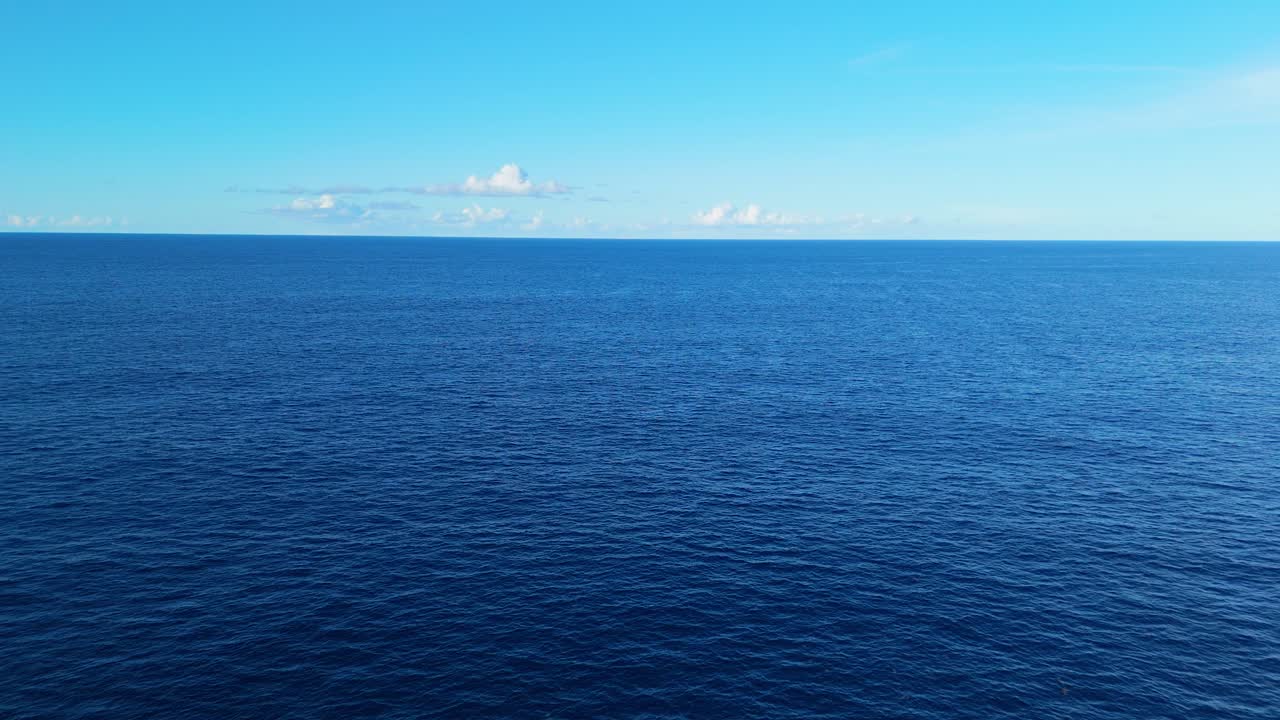 Slow aerial ascent pullback over calm ocean with a vast expanse of blue water, perfect for tranquil backgrounds