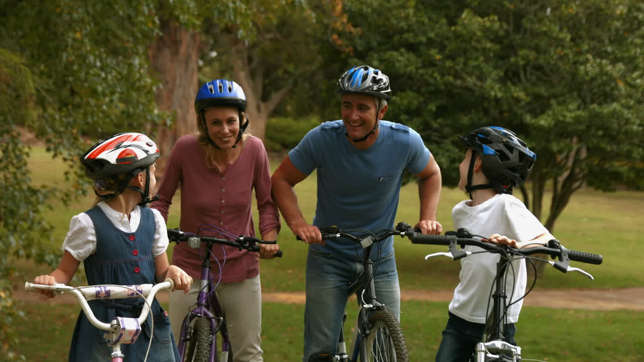 familia feliz en su bicicleta en el parque sonriendo a la cámara