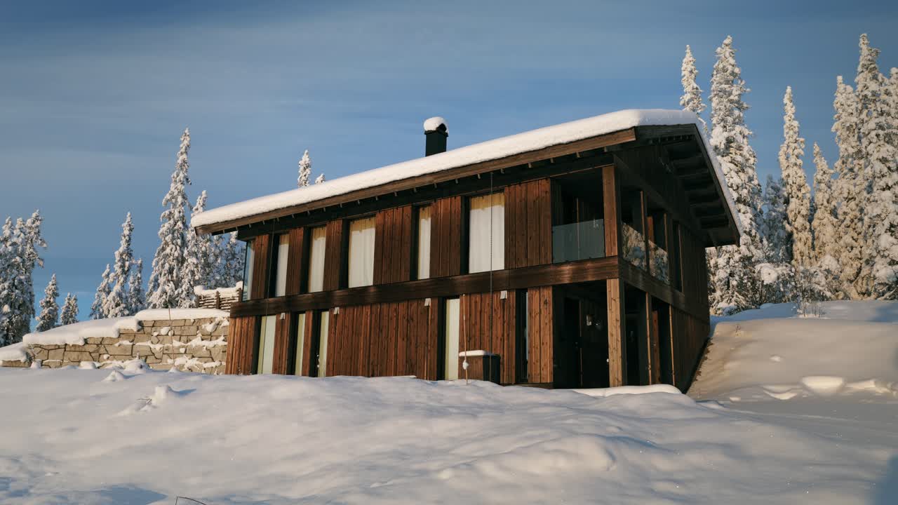 Pondok kayu Nordik modern yang nyaman di salju musim dingin yang tebal di hutan pinus pegunungan Alpen yang disinari matahari, Valdres, Norwegia