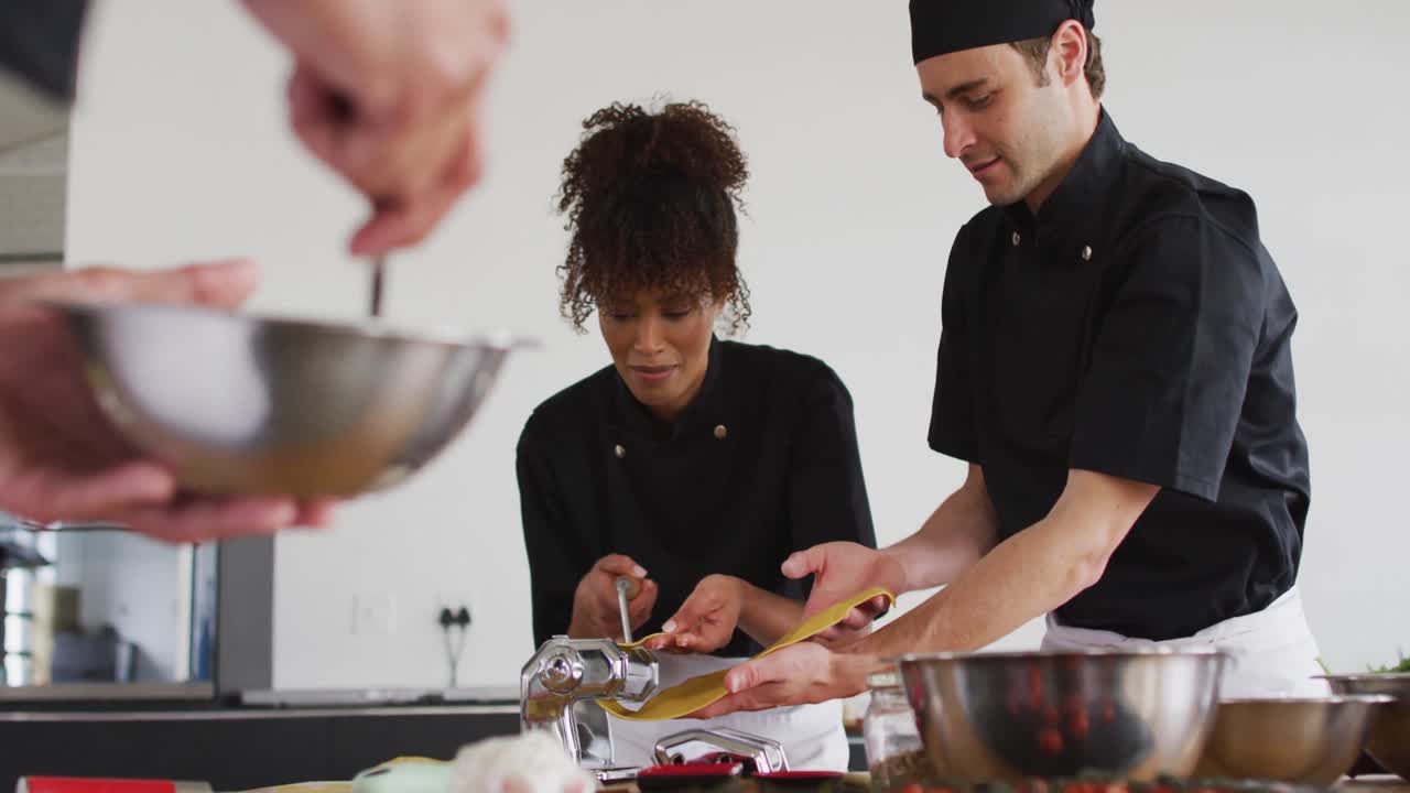 grupo diverso de chefs preparando platos y sonriendo en una cocina