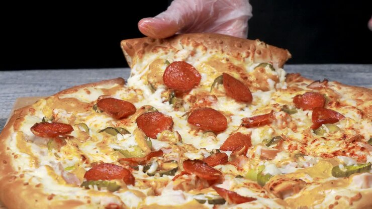 Mano che tiene una deliziosa fetta di pizza