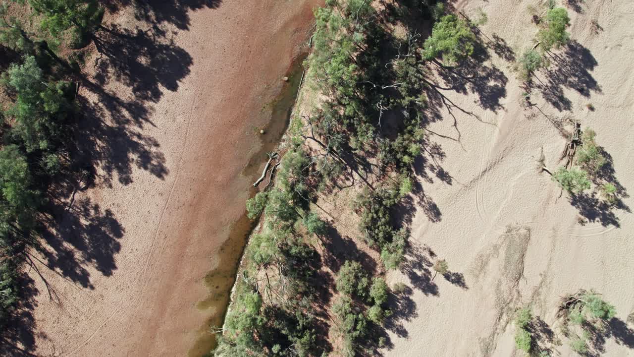 Slow moving vertical drone footage of the dry river bed of the Finke River near the Stuart Highway in the Northern Territory, Australia. August 2022.