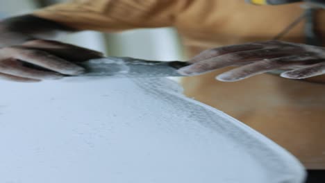 calm anonymous man shaping surfboard with instrument