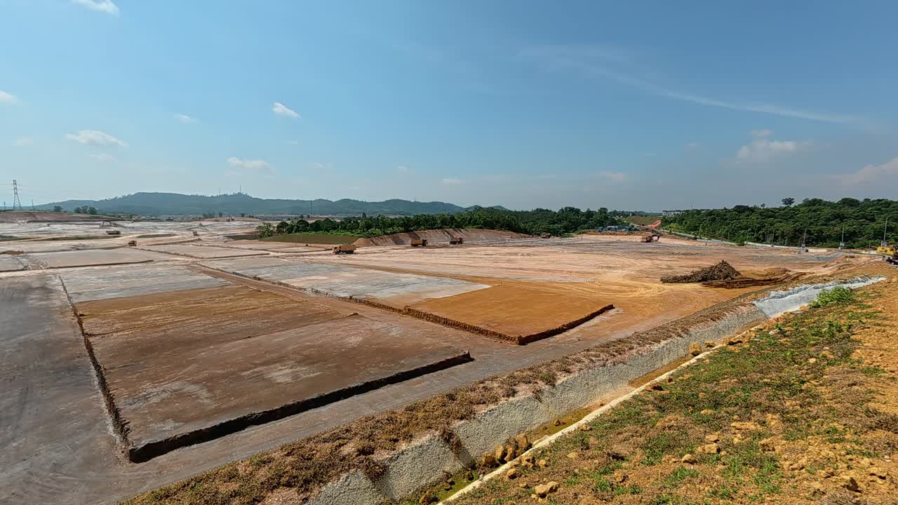 Extensive earthworks at a large construction site. Heavy machinery is used to level the ground, cutting into hills and filling in ravines to prepare the land for building new homes