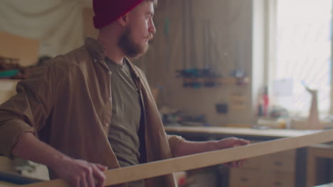 carpenter putting wooden plank on workbench