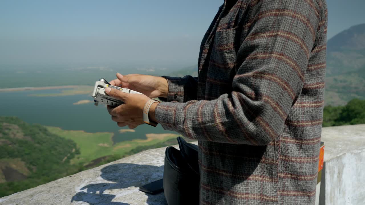 인도의 전문 드론 조종사가 야생동물 풍경에서 감시 비행을 한 후 드론 팔을 접고 있습니다.