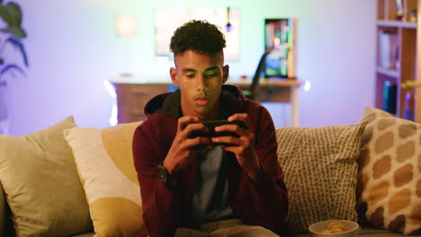 joven jugando en su teléfono inteligente en casa