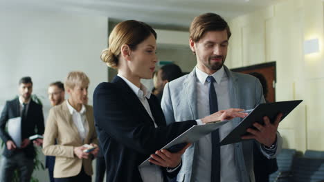 caucasian businesswoman and her male colleague talking and discussing documents in the hall at a meeting