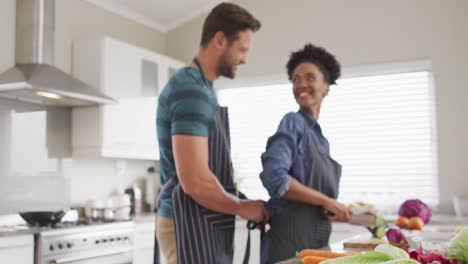 Video-Eines-Glücklichen,-Vielfältigen-Paares,-Das-Essen-Zubereitet-Und-Gemüse-In-Der-Küche-Schneidet