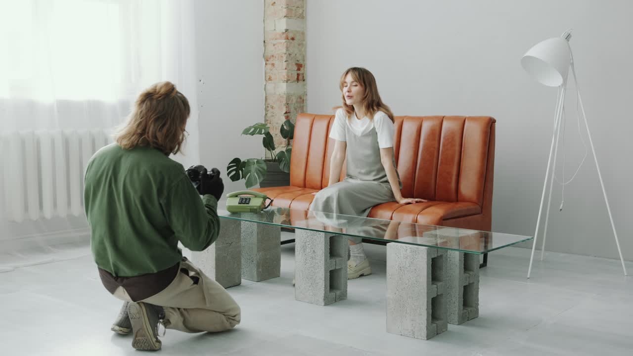 Photographer Capturing Woman Sitting on Couch in Minimalist Studio
