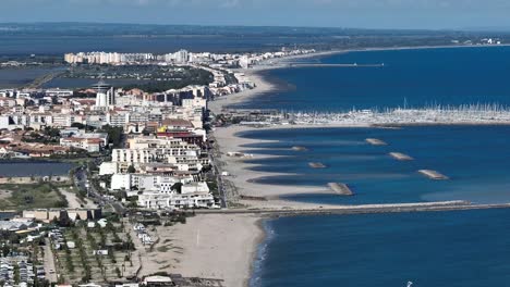 Coastal-town-of-Palavasles-Flots-in-southern-France-with-Iconic-Phare-tower-and-marina,-Aerial-dolly-right-shot