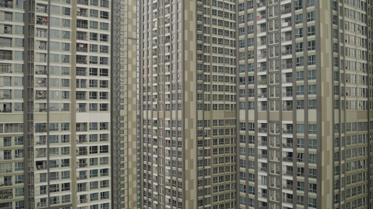 Towering residential apartment complexes dominate Saigon's urban landscape. Hundreds of windows create geometric patterns across massive concrete high-rise buildings in Vietnam's bustling metropolis.