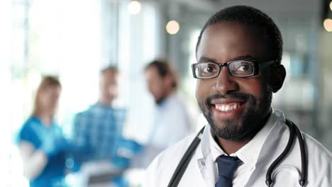 portrait of african-american physician in white gown and glasses looking at camera and smiling