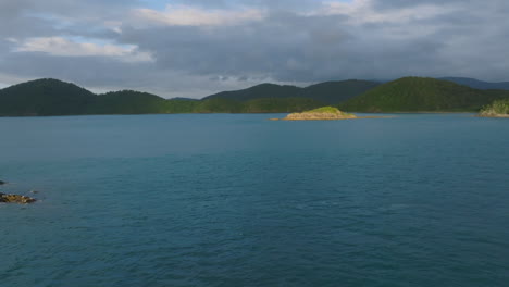 drone sliding past a rocky island lit up by the sunrise, whitsunday islands, australia