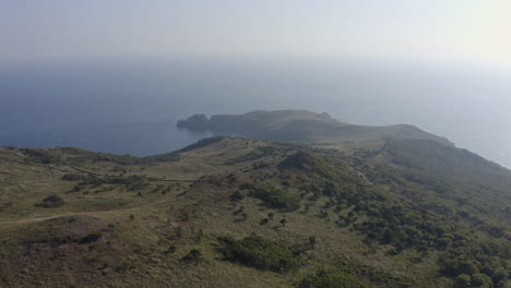 Landscape-open-shot-of-high-lands-with-green-fields-near-the-ocean-side,-on-a-bright,-clear,-sunny-day