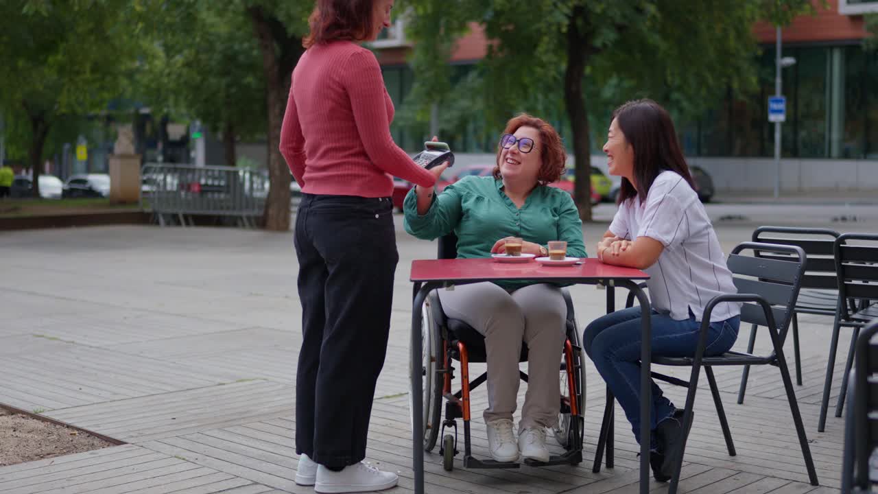 Amici che si godono un caffè in un bar all'aperto accessibile
