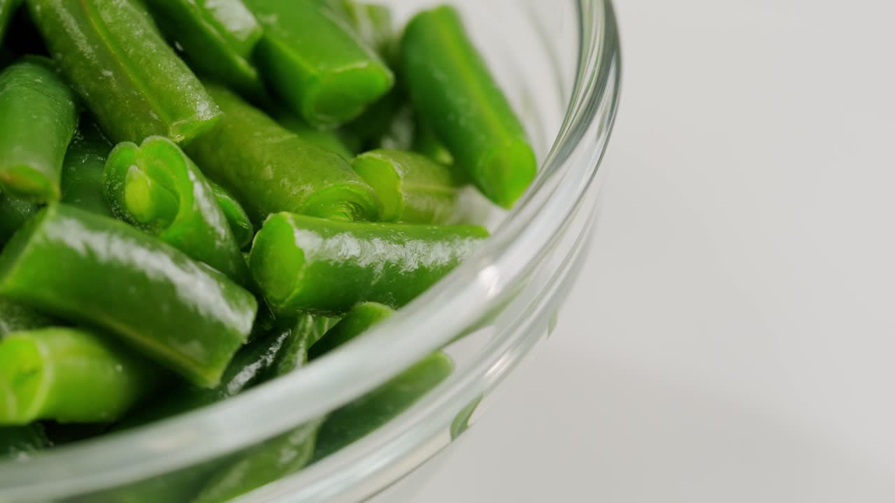 Fried wok green beans with onions and spices in a white plate on a gray background. Flat lay. Top view. High quality 4k footage