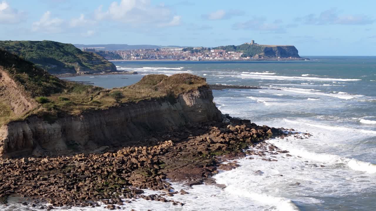 Riprese aeree con drone di Scarborough, effettuate da lontano su Cayton Bay, con cielo blu, oceano e grandi onde.