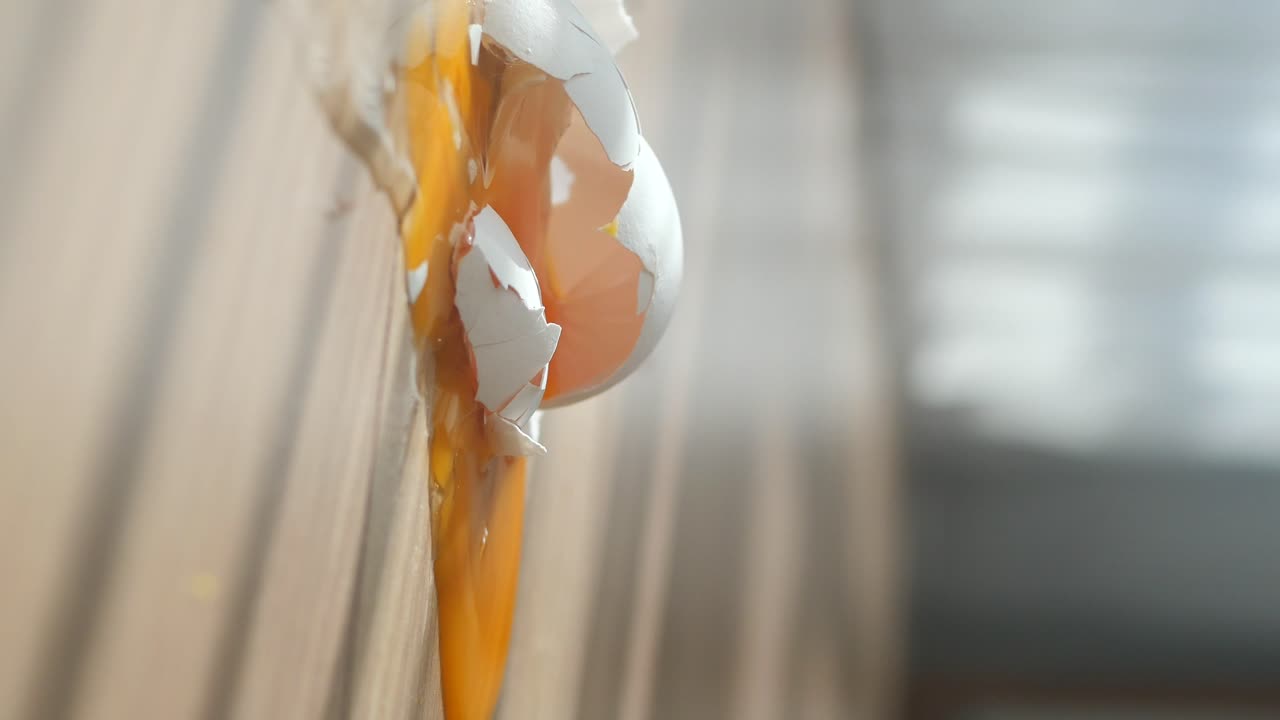 A Broken Egg with Yolk and Shells Spilling Down a Surface