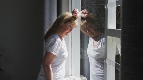 mujer mayor mirando por la ventana en casa