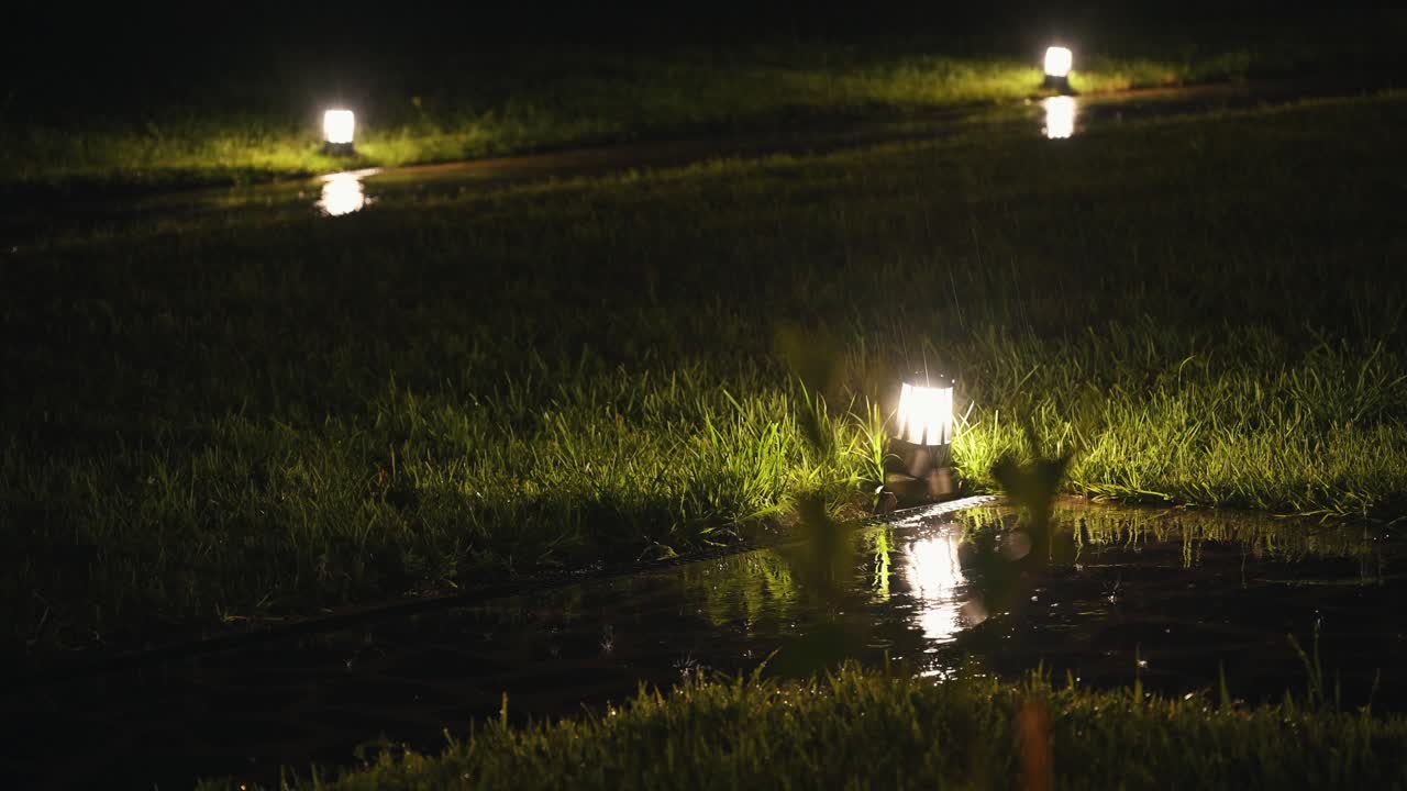 4k: gotas de lluvia cayendo sobre las luces del jardín durante una noche lluviosa